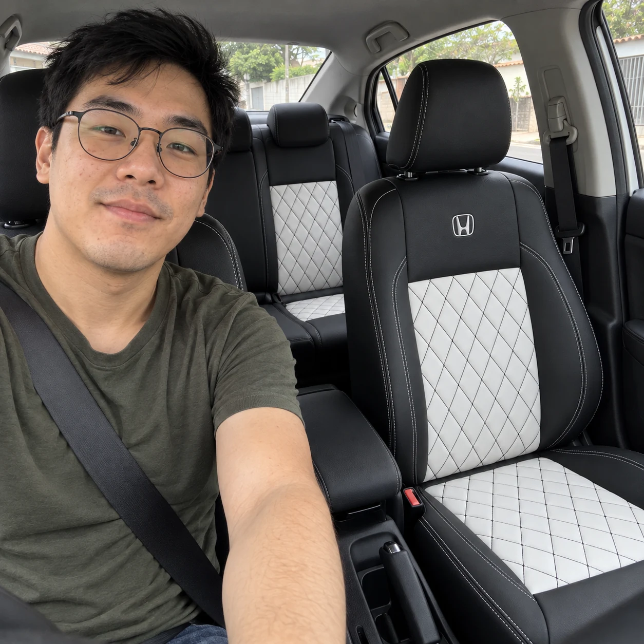 Felipe de óculos e camiseta verde no Honda City com bancos pretos com centro branco, costura Diamante e logo Honda bordada
